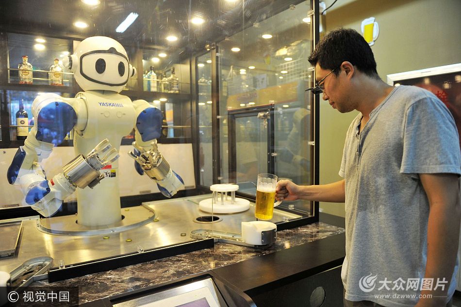 2017年8月6日,山東青島金沙灘啤酒城,顧客拿起機(jī)器人倒入啤酒的啤酒杯。