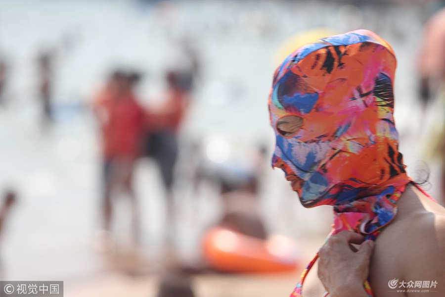 2018年7月6日,臉基尼大媽在青島第一海水浴場洗海澡。夏日炎炎,防曬神器臉基尼風(fēng)靡青島海灘,眾多中老年婦女頭戴五彩繽紛的臉基尼下海游泳健身,成為一道靚麗的風(fēng)景。